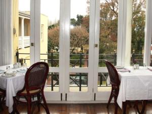 een eetkamer met een tafel, stoelen en ramen bij Zomerlust Boutique Hotel in Paarl