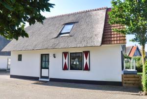ein weißes Haus mit roten Fenstern und einem grauen Dach in der Unterkunft Buitenplaats 86 in Callantsoog