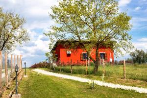 czerwony dom z drzewem obok drogi w obiekcie Agriturismo Poggio Degli Ulivi w mieście Bomarzo