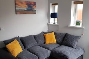 a gray couch with yellow pillows in a living room at Sea Reach Apartment, 2 minutes from beach and town in Newquay