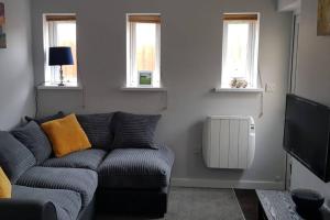 a living room with a couch and two windows at Sea Reach Apartment, 2 minutes from beach and town in Newquay