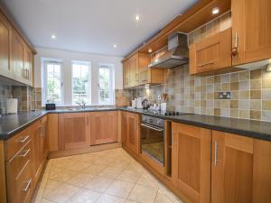 a large kitchen with wooden cabinets and black counter tops at 1 Buckfields in Lyme Regis