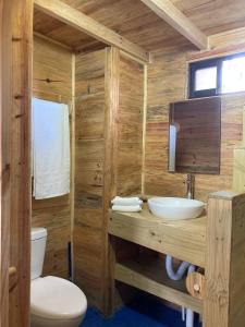 a wooden bathroom with a toilet and a sink at Bungalows Baobab in San Isidro de El General