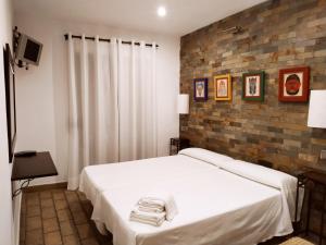 Estremera的住宿－埃爾康文圖旅館，卧室配有白色的床和砖墙