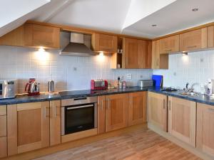 a kitchen with wooden cabinets and black counter tops at 13 Buckfields in Lyme Regis