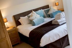 ein Bett mit blauen und weißen Kissen darauf in der Unterkunft Fistral hot tub house for 8 on Retallack Resort in Newquay + 25 Fotos