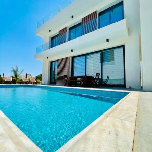 a villa with a swimming pool in front of a house at By the Beach Villa Natalya in Protaras