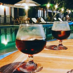 dos copas de vino sentadas en una mesa junto a una piscina en Panorama Ekas, en Ekas