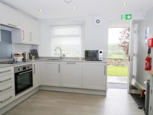 a white kitchen with a sink and a microwave at Oxen Park Farm Cottage in Ulverston