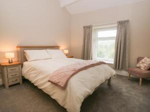 a bedroom with a bed and a window and a chair at Oxen Park Farm Cottage in Ulverston