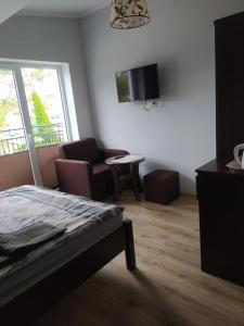 a bedroom with a bed and a chair and a tv at Sis Dziwnowek in Dziwnówek