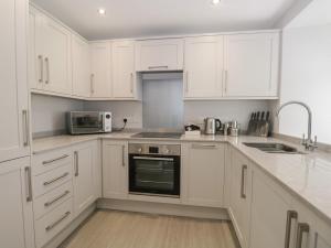 a white kitchen with white cabinets and a microwave at Bills Barn in Ulverston