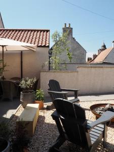 Culross的住宿－The Dundonald Guesthouse & Cottage，庭院配有两把椅子、一张桌子和一把遮阳伞