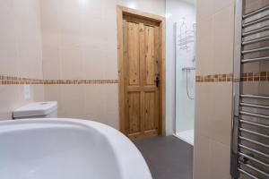 a bathroom with a toilet and a wooden door at The Holmes Barn - Sleeps 16 - Peak district in Buxton
