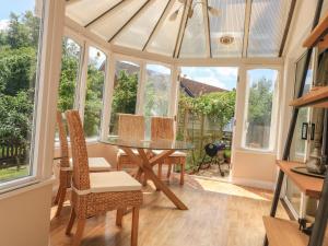 a conservatory with a table and chairs and windows at Birdsong in Crediton
