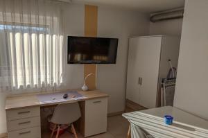 een kamer met een bureau en een tv aan de muur bij Business Apartment Reutlingen in Reutlingen