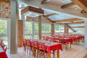 ein Raum mit Tischen und Stühlen in einem Raum mit Fenstern in der Unterkunft VVF Corrèze Pays d'Eygurande in Eygurande