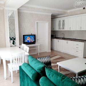 ein Wohnzimmer mit einem grünen Sofa und einer Küche in der Unterkunft Comfortable apartment in Bischkek