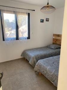 two beds in a room with two windows at Brindingaccia in Propriano