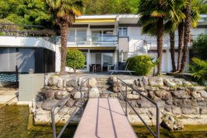 ein Haus mit Palmen und einem Holzsteg in der Unterkunft Bellariva Lakefront by Quokka 360 - flat with private pier in Montagnola