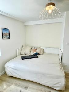 una camera da letto con un grande letto bianco con luce di Faubourg des voyageurs n°5 a Saran