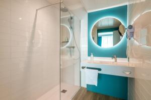 a bathroom with a sink, mirror, and bathtub at Holiday Inn Reims Centre, an IHG Hotel in Reims