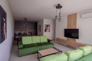 a living room with a green couch and a kitchen at Vertmont Villa in Sveti Stefan
