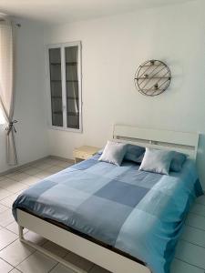 a bedroom with a large blue bed with a clock on the wall at APPARTEMENT SPACIEUX in Orange