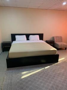 a bedroom with a large bed and a chair at Sky Inn Hotel in Freetown