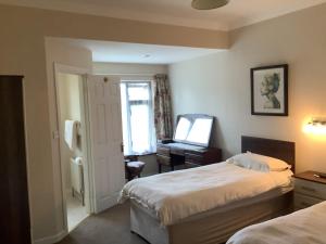 a bedroom with two beds and a desk and a mirror at Palmgrove Bed & Breakfast in Listowel