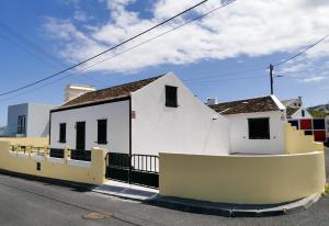ein weißes Gebäude mit einem Zaun neben einer Straße in der Unterkunft Aurora House in Mosteiros