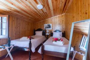 zwei Betten in einem Zimmer mit Holzwänden in der Unterkunft Aurora House in Mosteiros