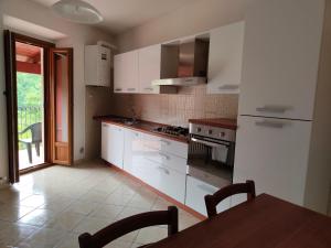 a kitchen with white cabinets and a wooden table at Il Narciso appartamenti in Assergi