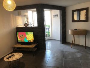 sala de estar con TV en una pared de ladrillo en Super beau studio en Port-la-Nouvelle