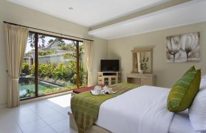 a bedroom with a large bed and a large window at Villa Tulip in Sanur