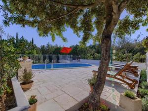 un patio con un árbol y una piscina con una sombrilla roja en Villa Vera, en Lovište