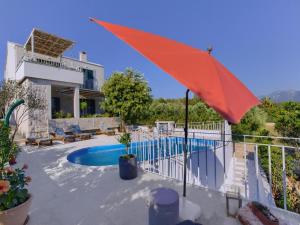 a pool with a red umbrella next to a house at Villa Vera in Lovište