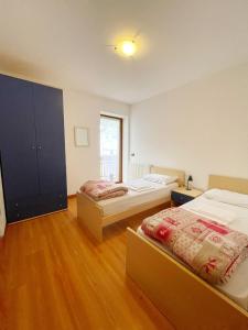 two beds in a room with wooden floors at Casa Nili in Alleghe
