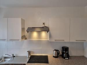 a kitchen with white cabinets and a stove top oven at Relax City Apartments in Kehl am Rhein