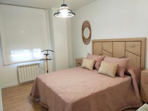 sypialnia z łóżkiem z różową pościelą i lustrem w obiekcie Apartamento Sofía w mieście Llanes