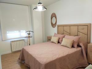 a bedroom with a bed with pink sheets and a mirror at Apartamento Sofía in Llanes +30 photos