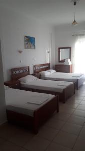 a room with three beds and a television in it at Sunset Apartments in Kanali