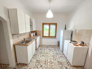 a kitchen with white cabinets and a tile floor at BDCSNY Apartman in Badacsonytördemic