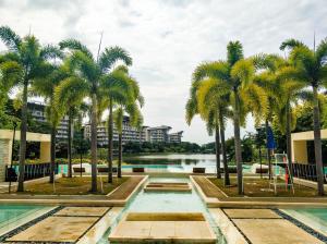 una piscina con palme di fronte a un bacino d'acqua di Beach Getaway at Pico de Loro Hamilo Coast Nasugbu Batangas a Nasugbu