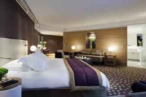 um quarto de hotel com uma cama grande e uma sala de estar em Hôtel Barrière Lille em Lille