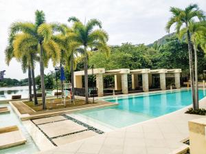 una piscina con palme e un edificio di Beach Getaway at Pico de Loro Hamilo Coast Nasugbu Batangas a Nasugbu