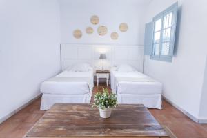 una habitación con camas blancas y una mesa con flores en Apartamentos Suites Santa Cruz en Sevilla