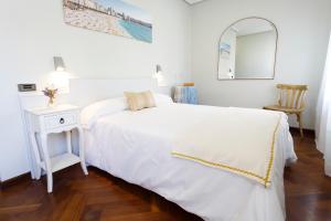 a white bedroom with a white bed and a mirror at Hostal Costa Coruña in A Coruña