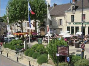 a town square with people sitting at tables and umbrellas at Le Petit Cesar in Hautvillers