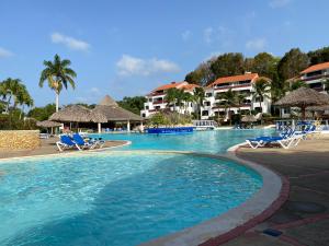 een zwembad in een resort met stoelen en palmbomen bij Flat Aquamare Monte Vista in Sosúa